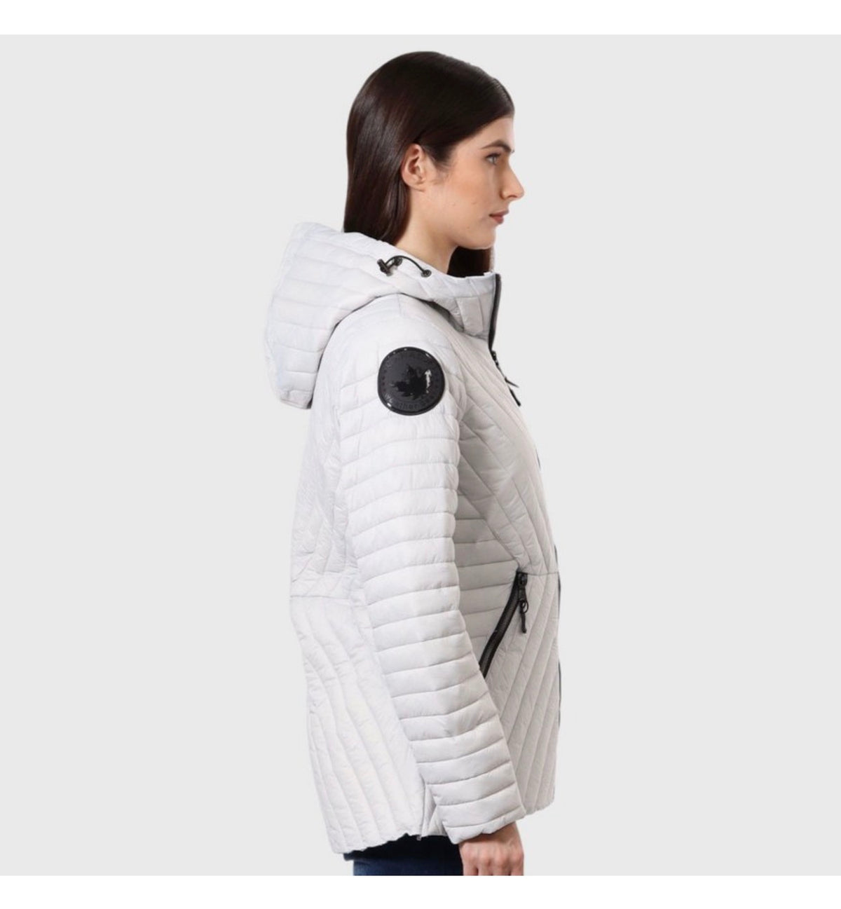 Woman wearing white quilted puffer jacket with hood and Canada-goose-style shoulder patch, side profile view. ##White
